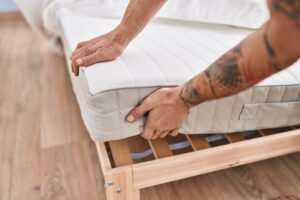 Young Man Holding Mattress Bedroom