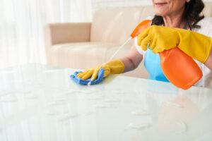 cropped woman spraying detergent coffee table