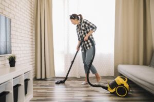 full shot woman vacuuming living room 1