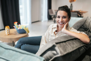 resting smiling young woman sitting home sofa