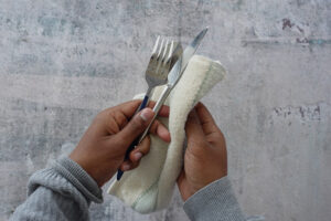 person hand cleaning drying cutlery with towel