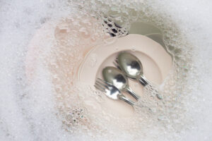 washing dishes close up utensils soaking kitchen sink