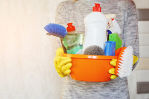 woman hands holding tub with cleaning supplies